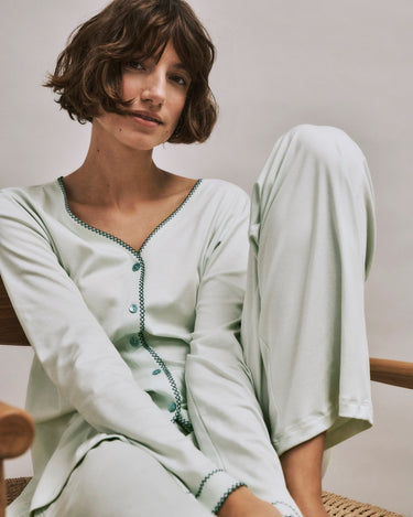 Woman wearing a light green Una pajama set sitting on a chair.